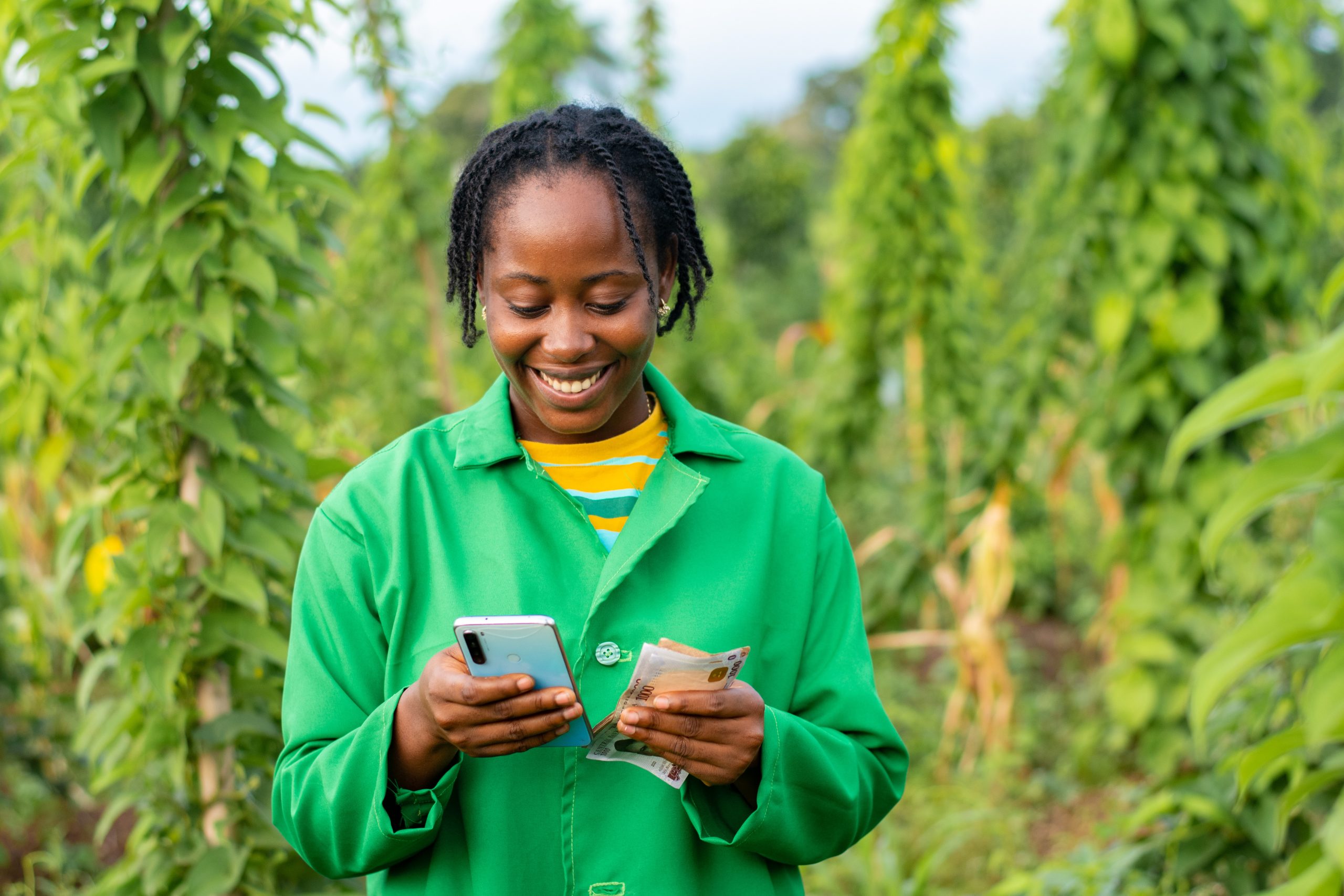 A cheerfl African farmer counting money on the phone calculator