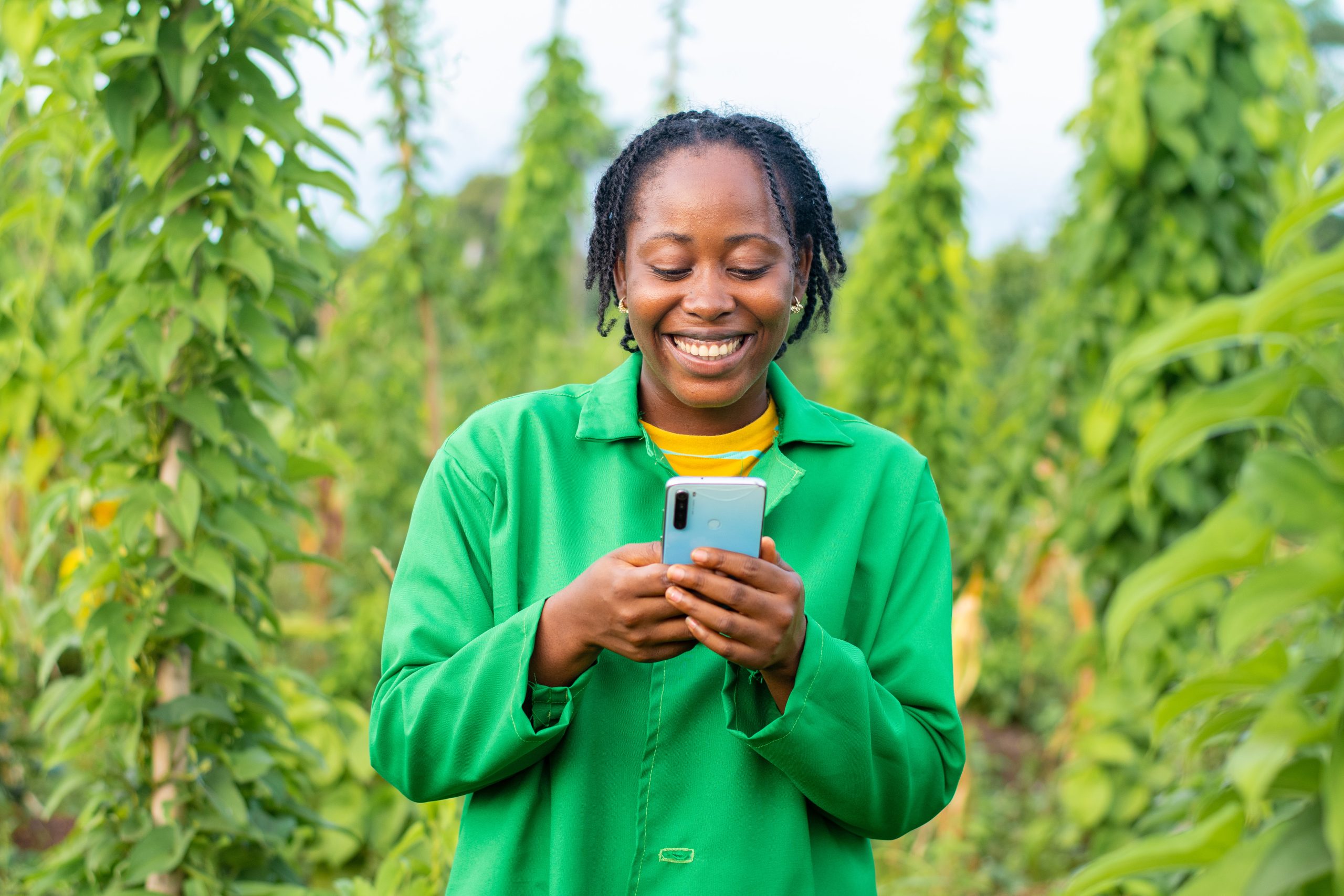 A shot of a happy female African farmer in Nigeria using her smartphone
